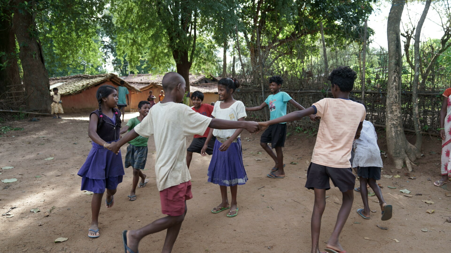 8 young Indian children play Ring a roses in a rural village setting