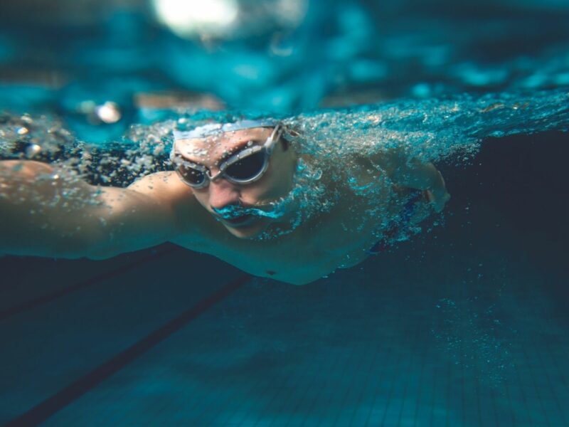 A person with goggles swimming in a swimming pool