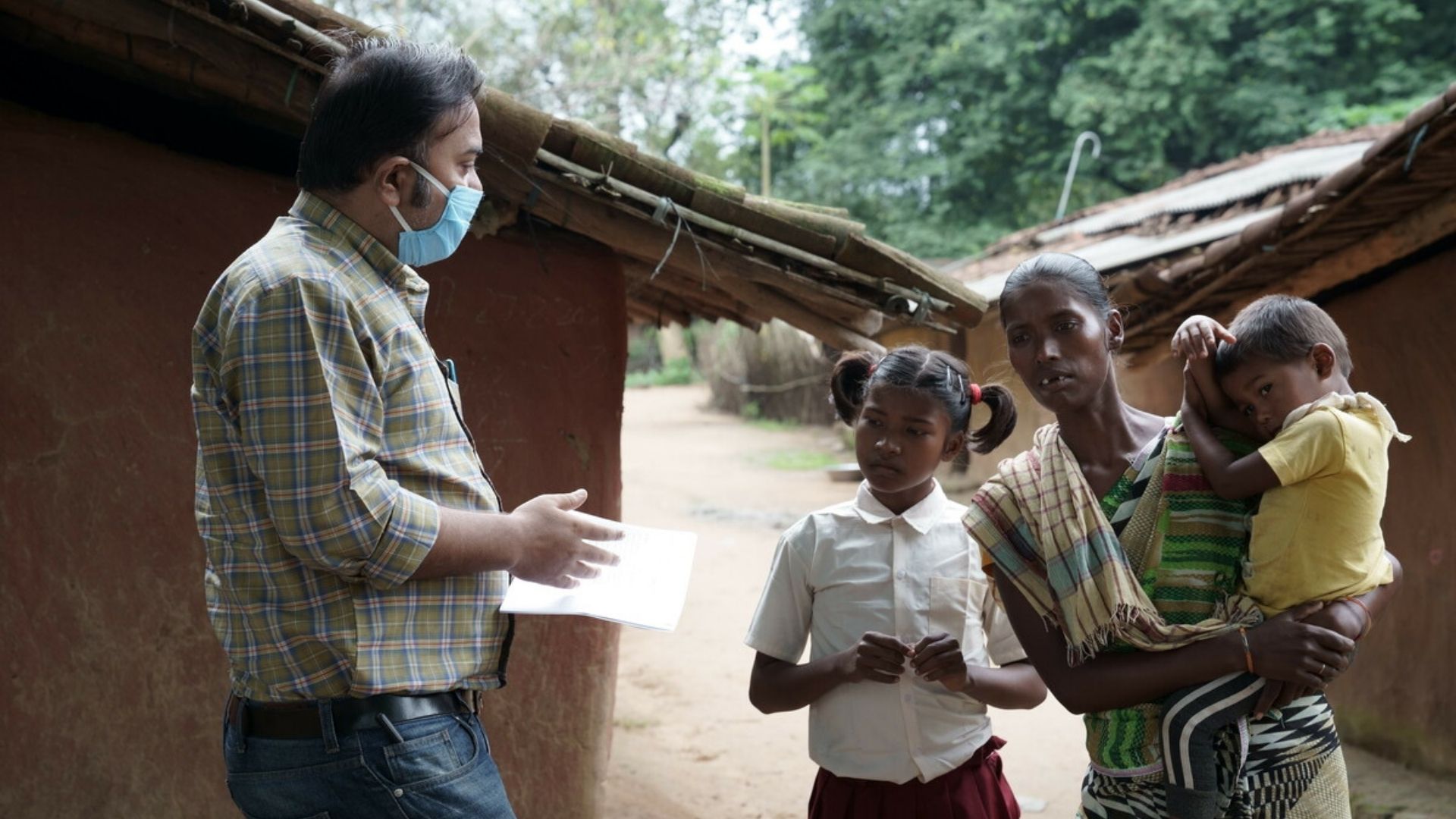 Sonia, her mum and her baby brother talking to someone from our partner organisation, CINI