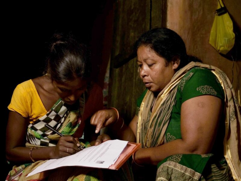 Preethi, a community volunteer from our local partner, Children In Need Institute (CINI), helps Radha* (Sonia's* mum) to fill in the application form for government support schemes she is eligible for.
