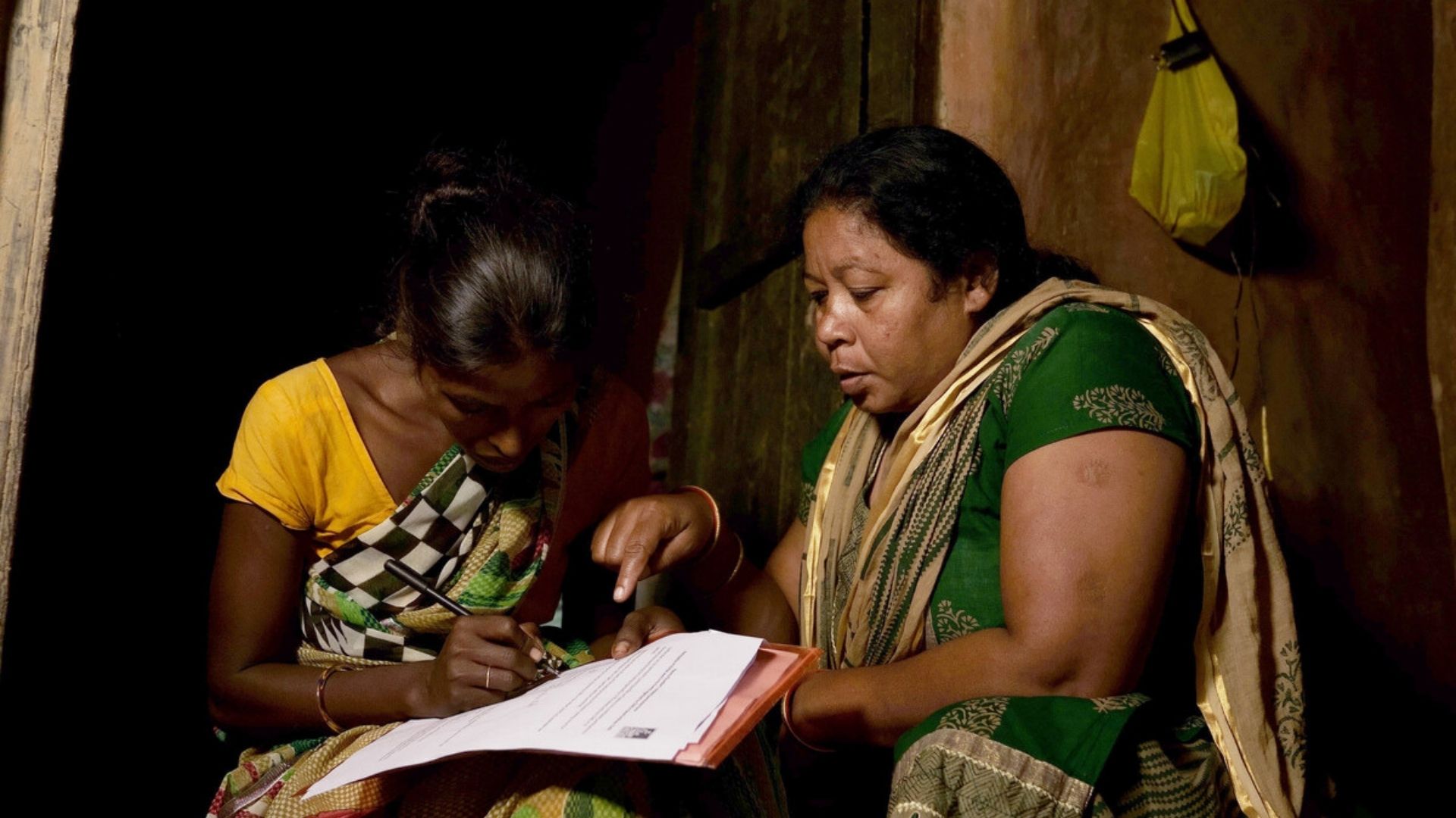 Preethi, a community volunteer from our local partner, Children In Need Institute (CINI), helps Radha* (Sonia's* mum) to fill in the application form for government support schemes she is eligible for.