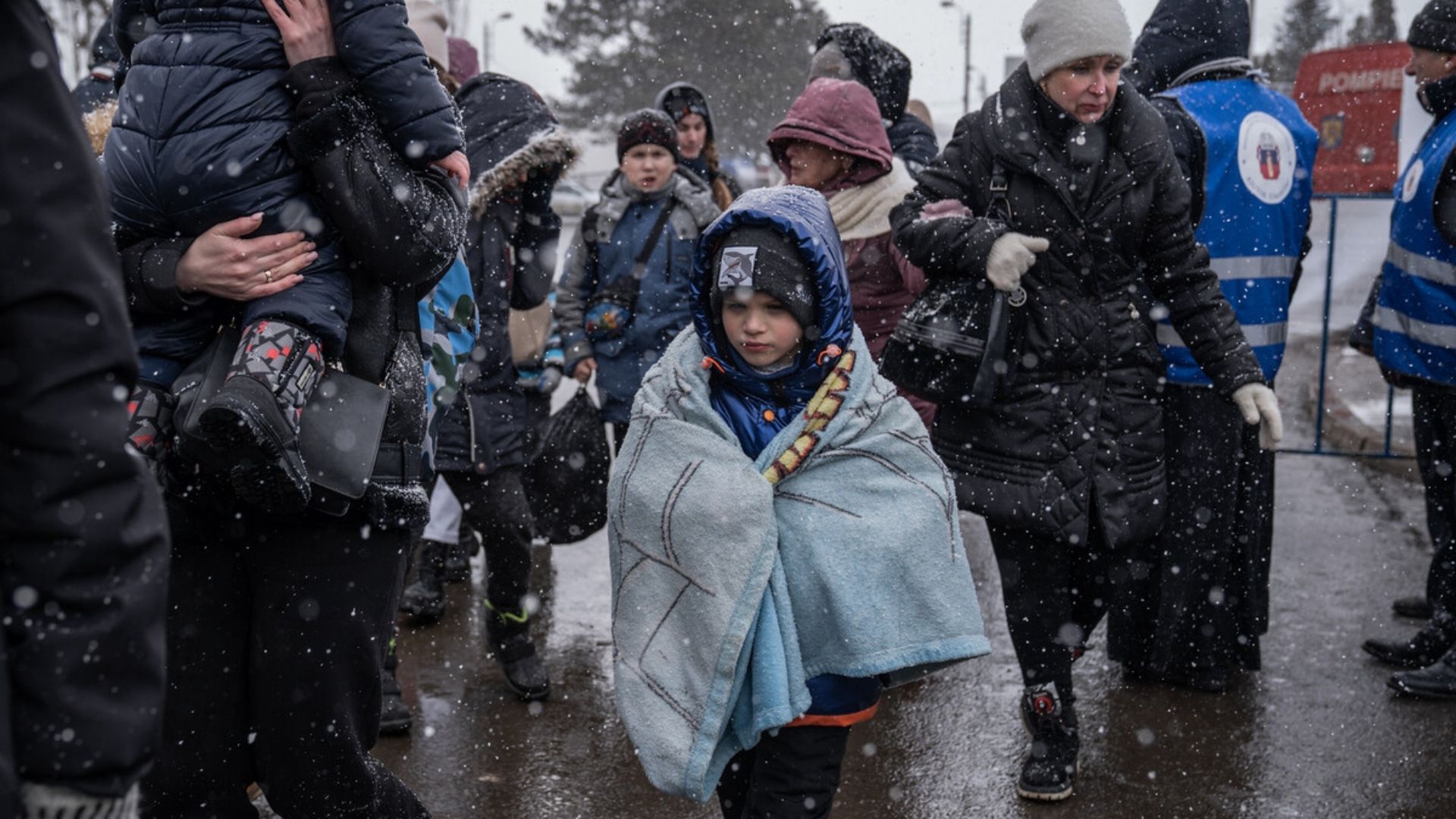 A child wrapped in blankets fighting his way through snowfall on the Ukraine-Romania border