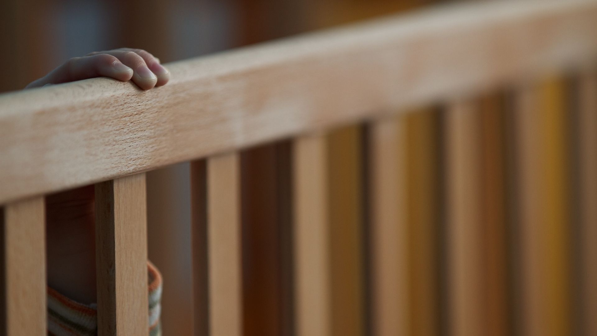 A child reaching out of a cot in an orphanage
