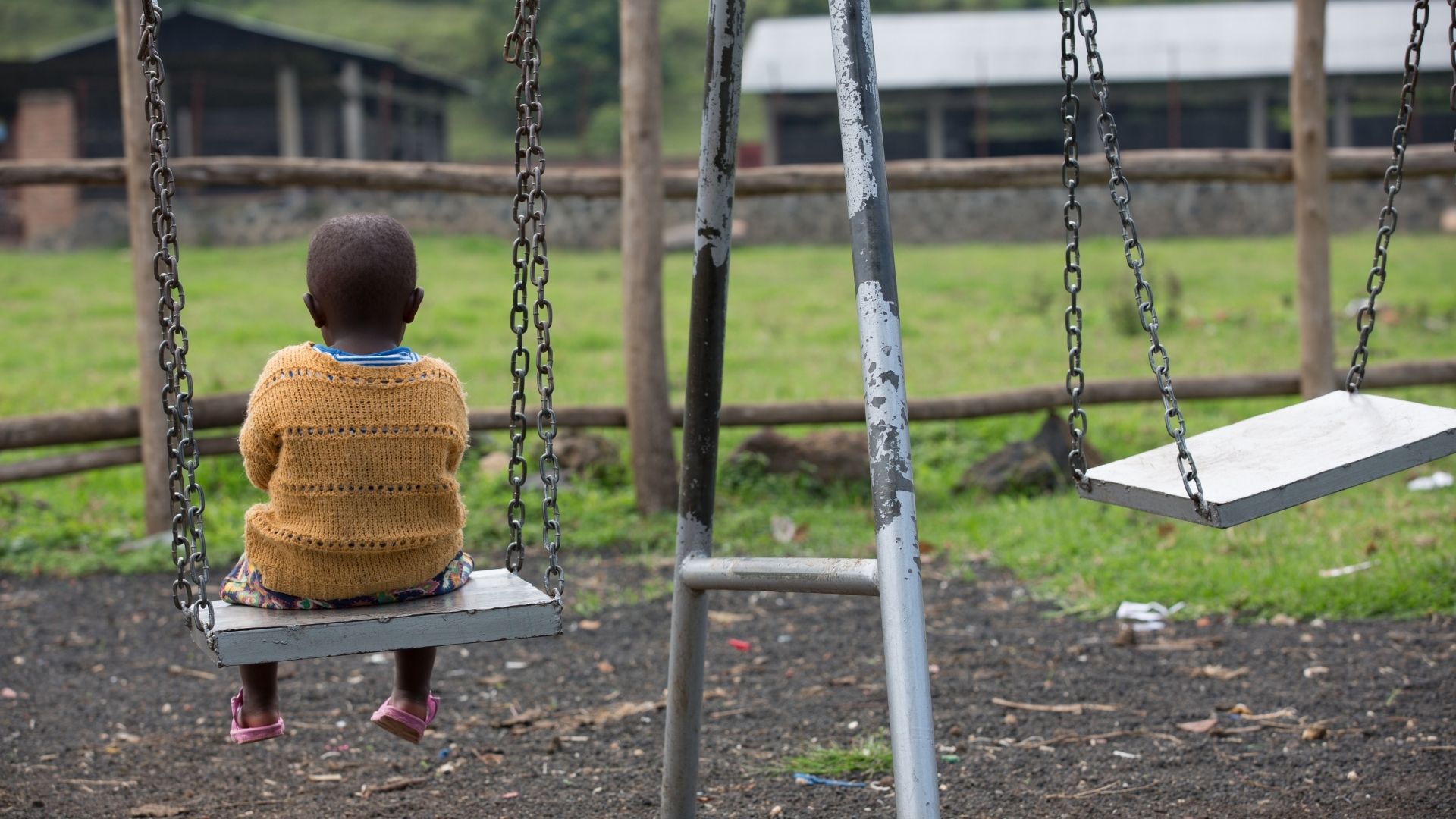 A picture of a child sitting on a swing alone, from our programmes in Rwanda