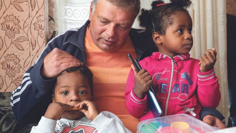 Kaloyan and Maria sit on their step father's lap