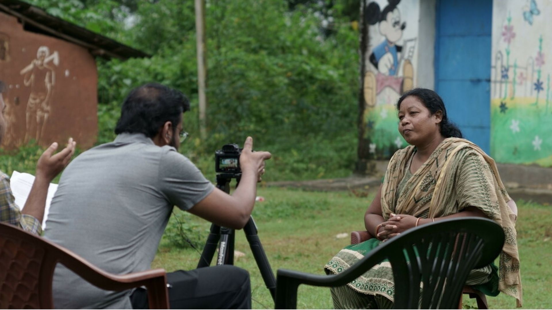 Preethi, a social worker with CINI India, being interviewed by two men, one who has a camera