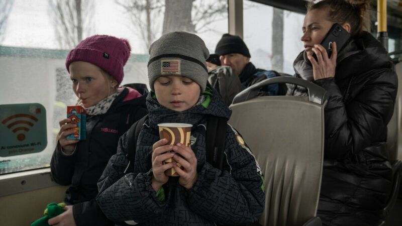 A refugee child from Ukraine on a train with a cup in his hands