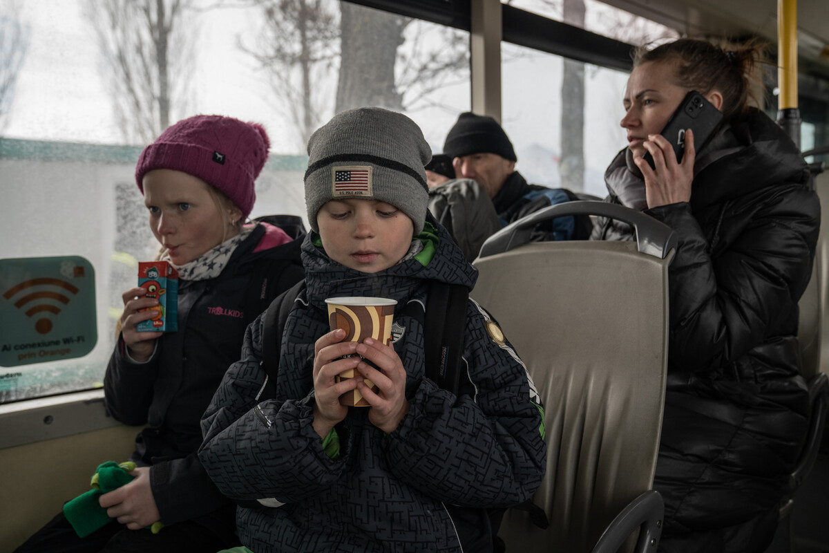 A refugee child from Ukraine on a train with a cup in his hands