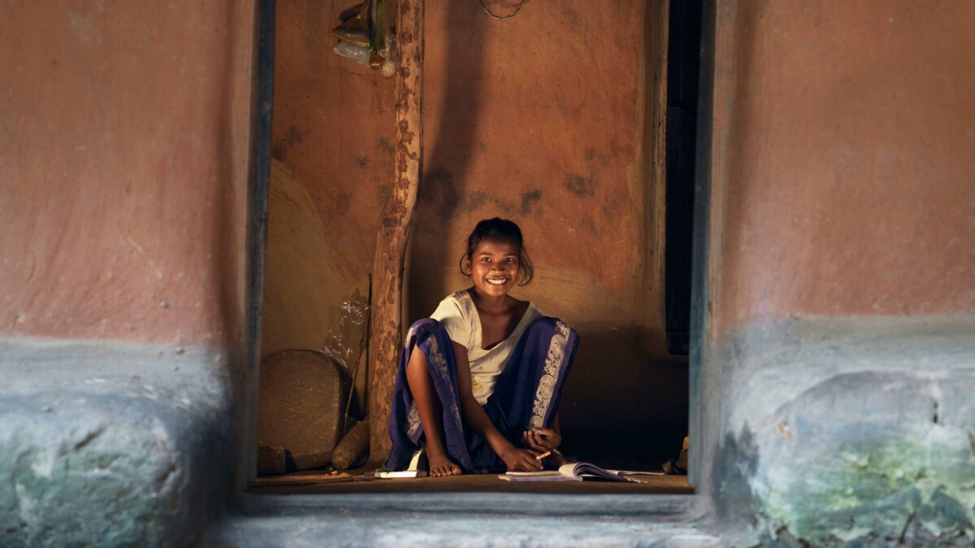 Sonia sitting outside her house, doing homework.