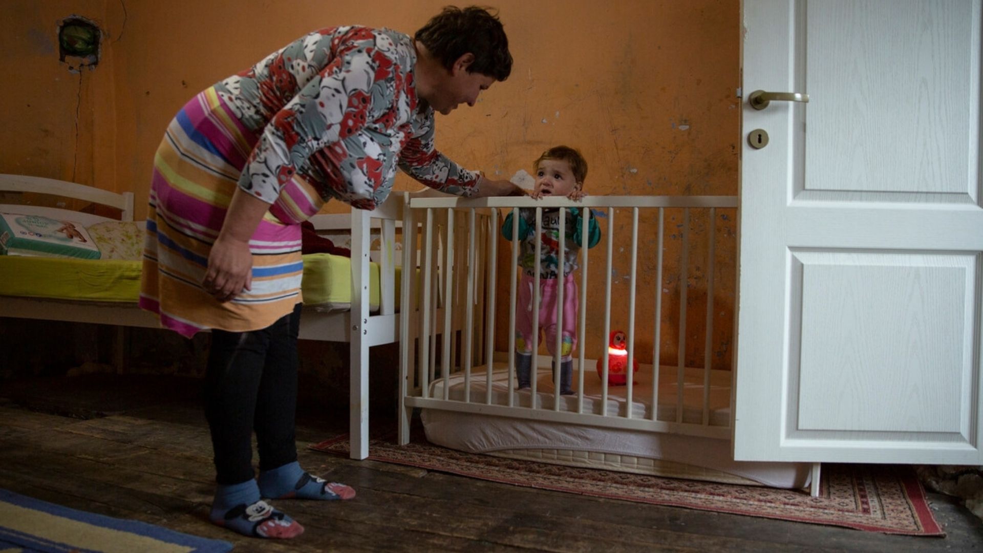 Ioana Petrică talks to her child in the cot in the bedroom