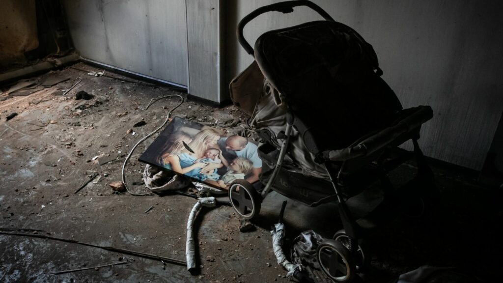 A pram and a photograph of a family lying broken in the ruins of a building in Ukraine