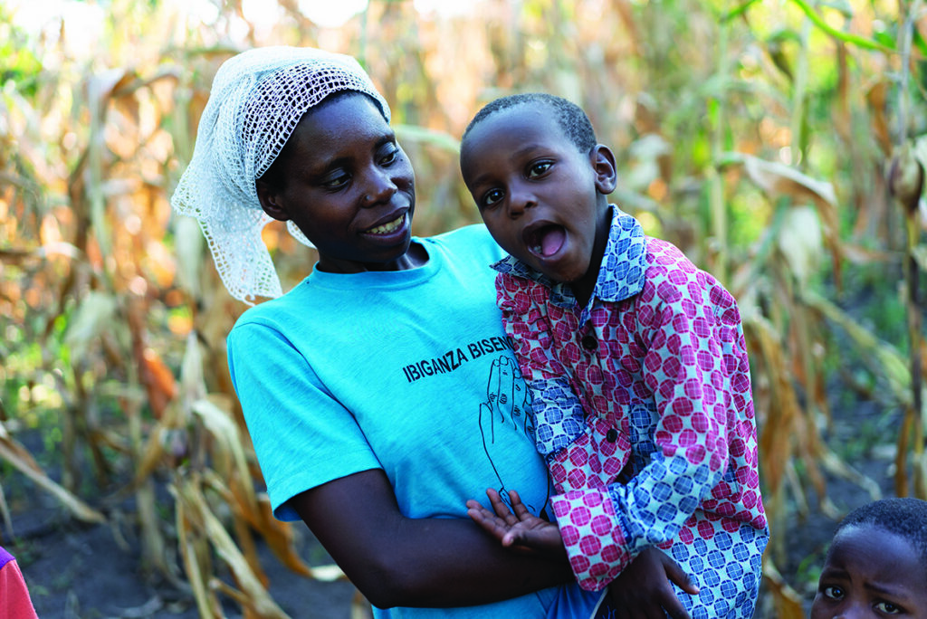 Carrol's mum, Mubyeyi, smiles at him as she holds him in her arms