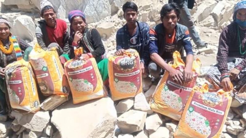 Parents of reunified children sit with bags of rice in a village in Humla.