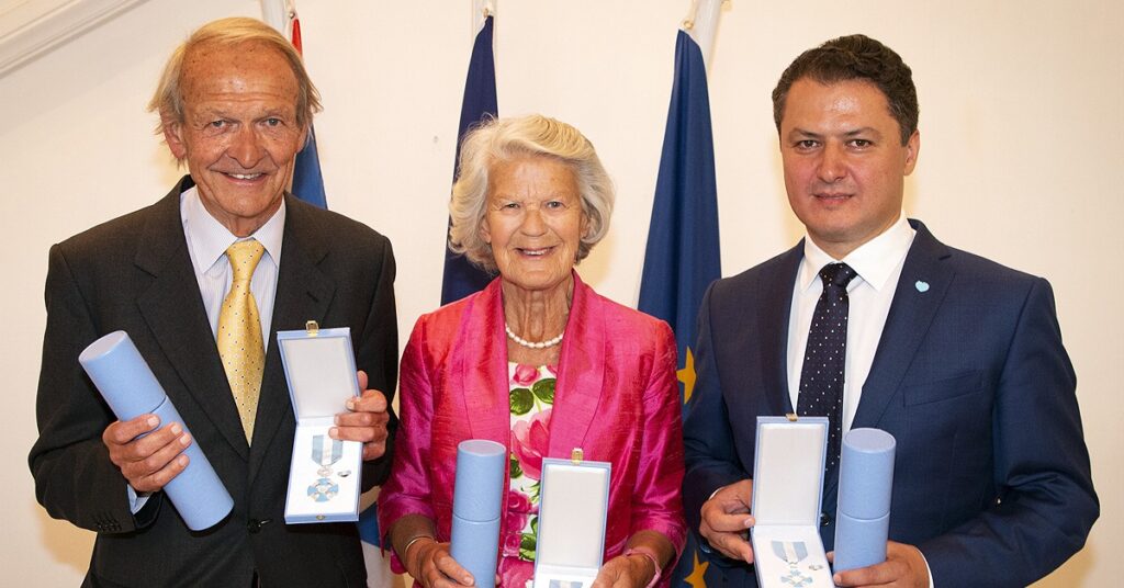 Mark and Caroline cook standing next to Stefan Darabus, all holding medals for their work for children in Romania