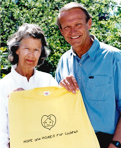 Mark and Caroline holding a yellow Hope and Homes for Children t-shirt