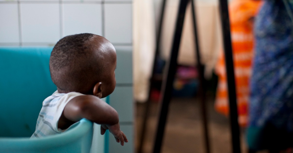 A baby leaning out of a plastic blue tub