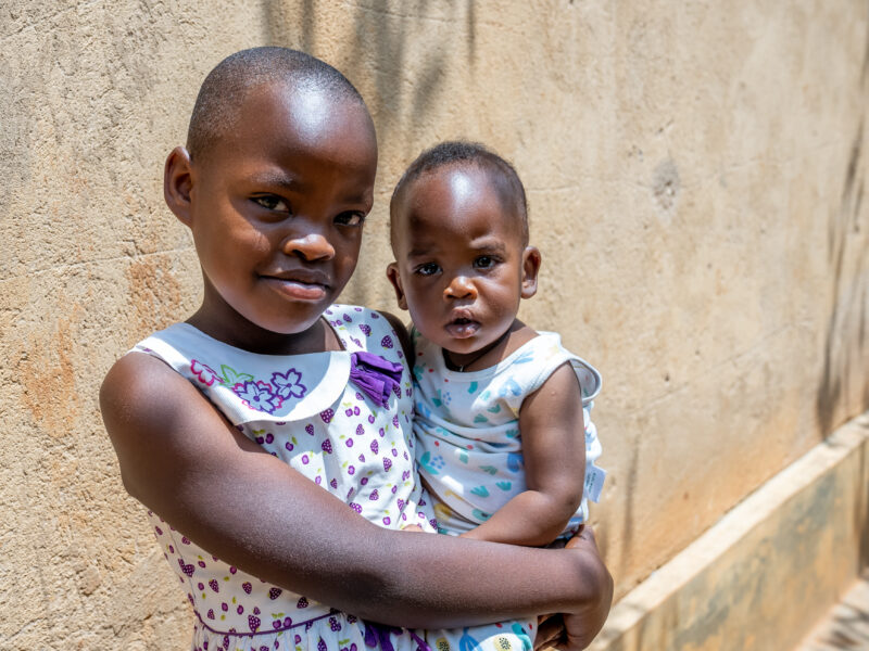 Young Rwandan care leaver holds her sister in her arms, now she has a family to be part of
