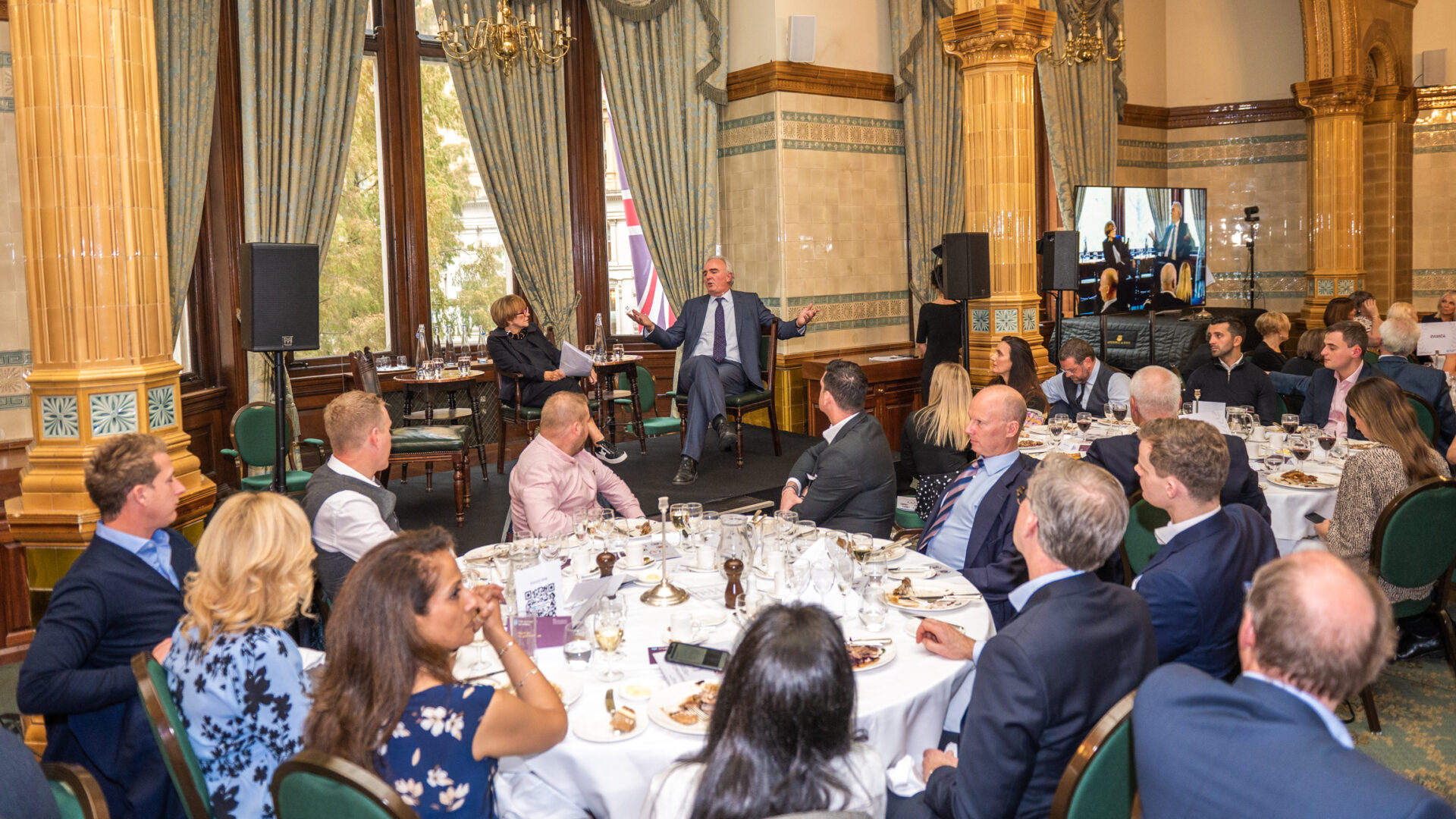 Group of people around a table, listening to a speaker