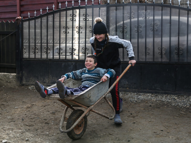 Two children playing with a wheelbarrow