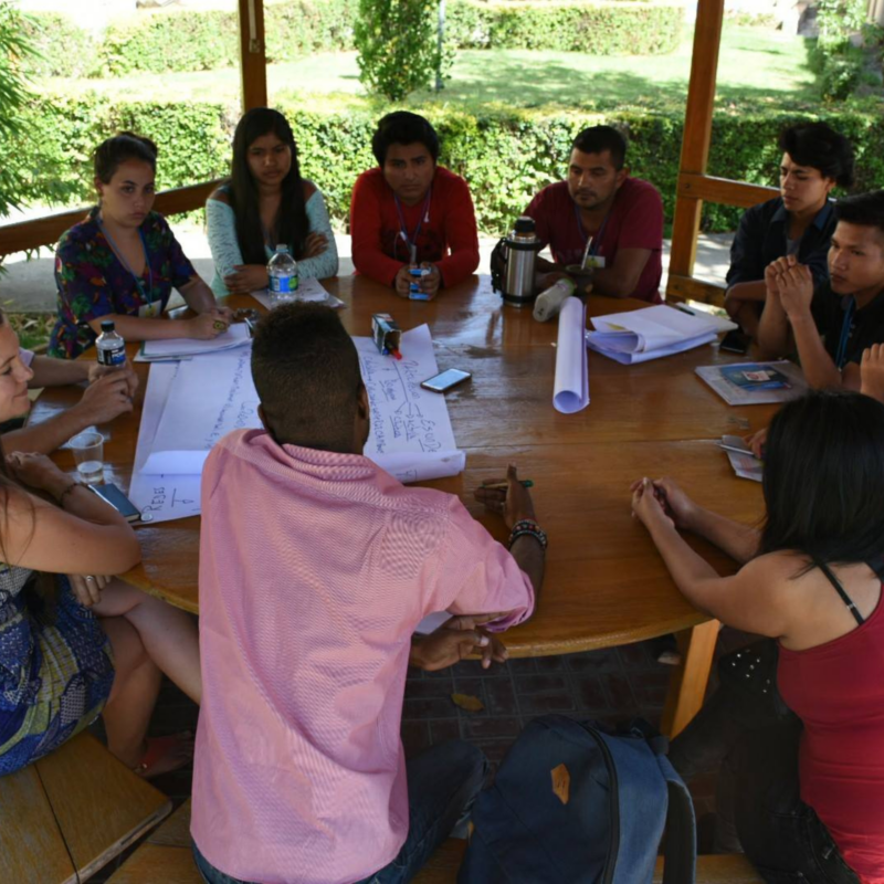 Group of young people sat around a table having a discussion