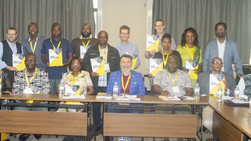 Group of Kenyan and Rwandan representatives smiling around a conference table