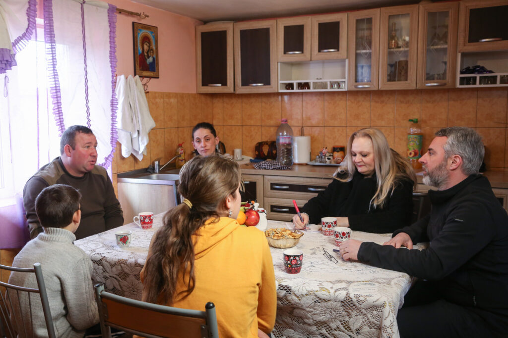 Radu, Simona and the Vancea family chatting and drinking tea round the kitchen table
