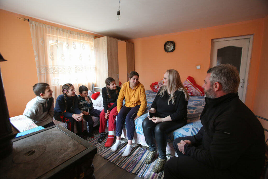 Children sat on a bed speaking to their social worker, Simona