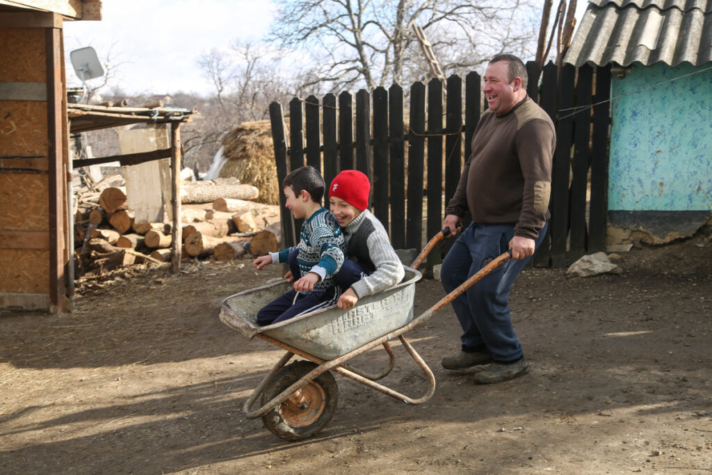 Ion pushing Nelu and his elder brother, Valer, 10, in a wheelbarrow in their backyard