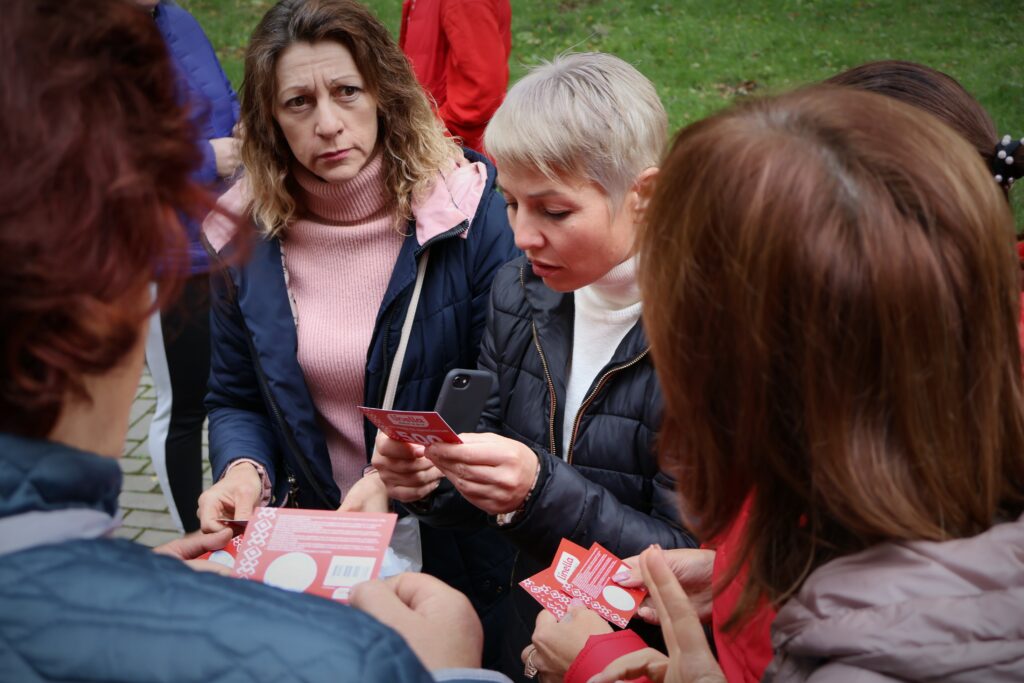 Moldovan women stand outside in a group, sharing information on the food voucher scheme
