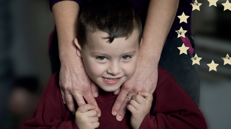 Young boy smiling holding hands with his parent