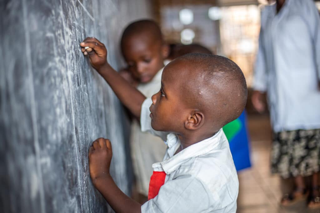 Image is of a child writing on chalk board