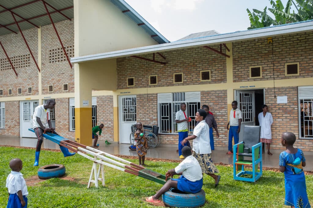 Image is of children playing at Maman Kiki's Community Hub. Two of the children are playing on a see saw.