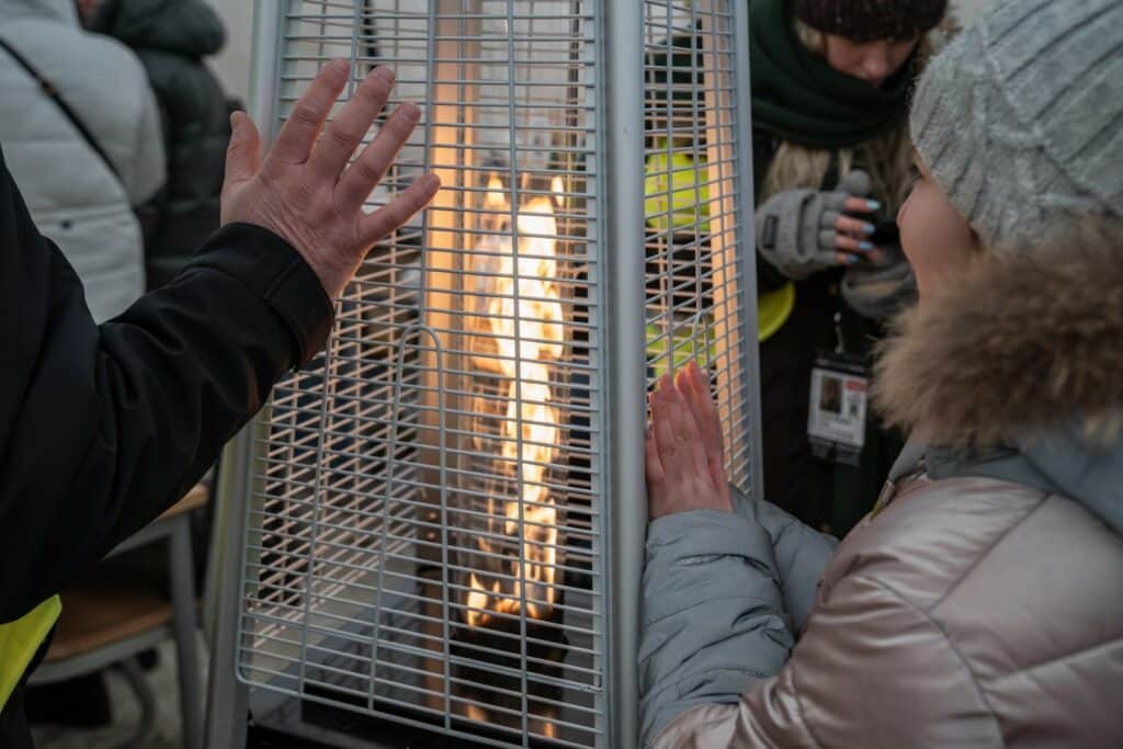 Displaced Ukrainians warming their hands on the Romanian border.