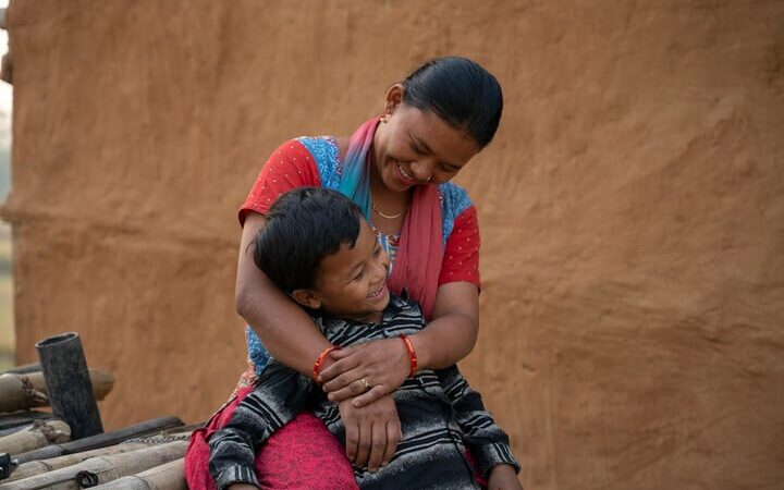 Sunil, a young Nepali boy who grew up in an orphanage, is held by his mum. Lata.