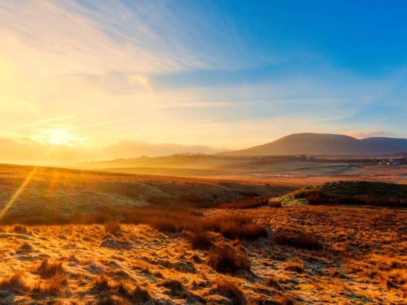 A glorious sunrise in the heart of the yorkshire dales with crisp blue skies and the mountains in the distance