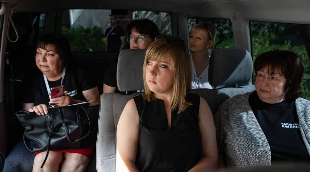 A group of Mobile Team social workers travelling to a community in crisis. They all look out the window together in concern.