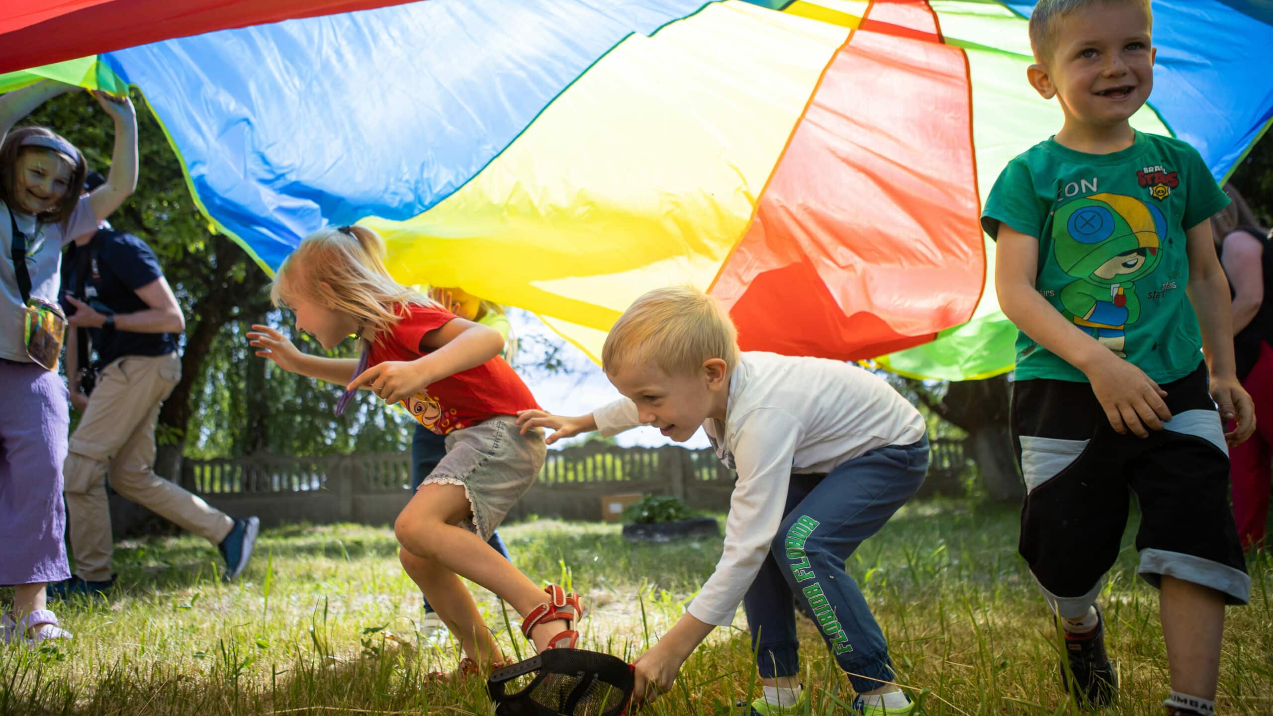 Children in Ukraine play happily under a multicoloured parachute.