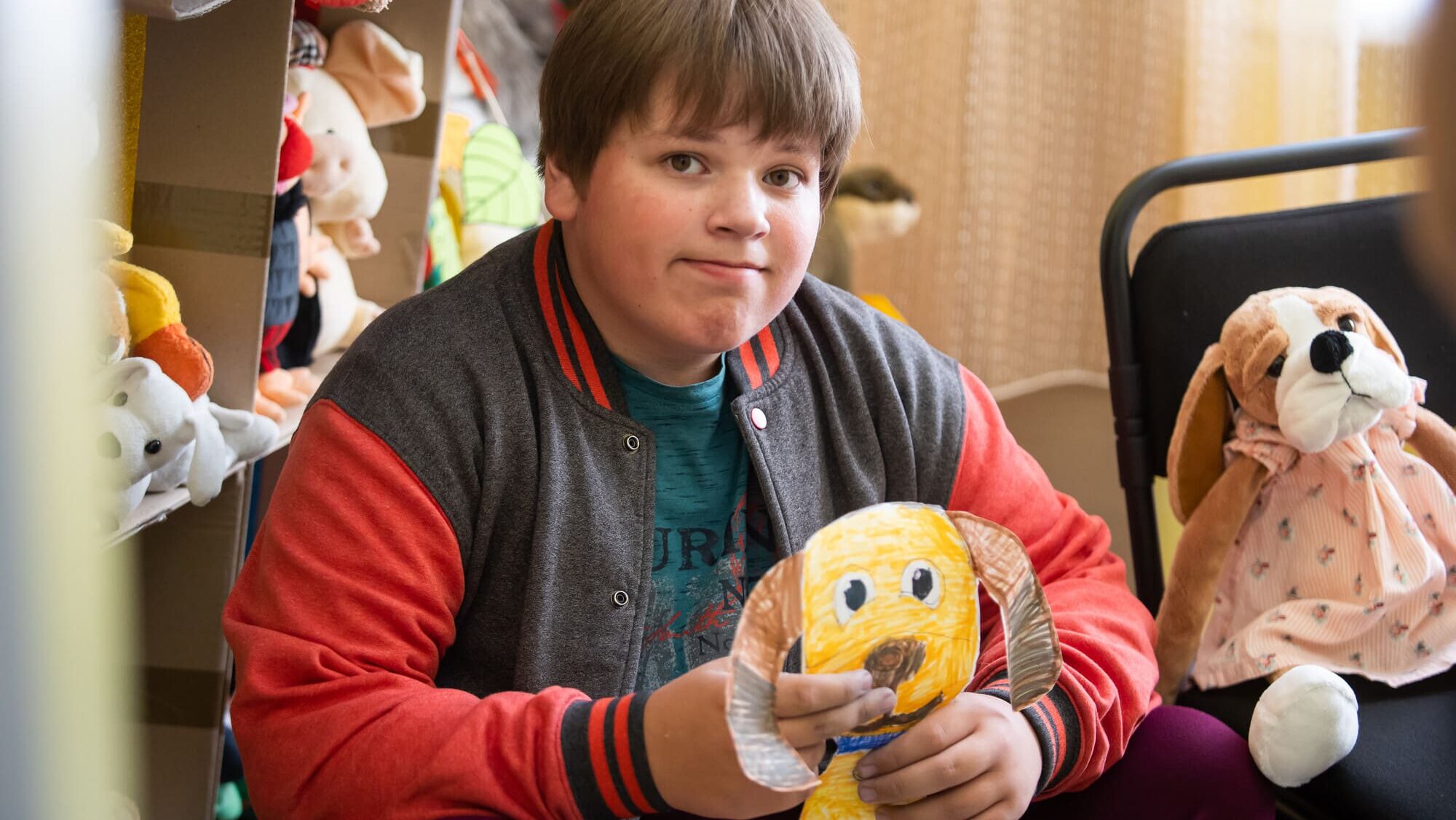 Andrii*, a Ukrainian boy with autism, clutches his drawing of a hibuki dog