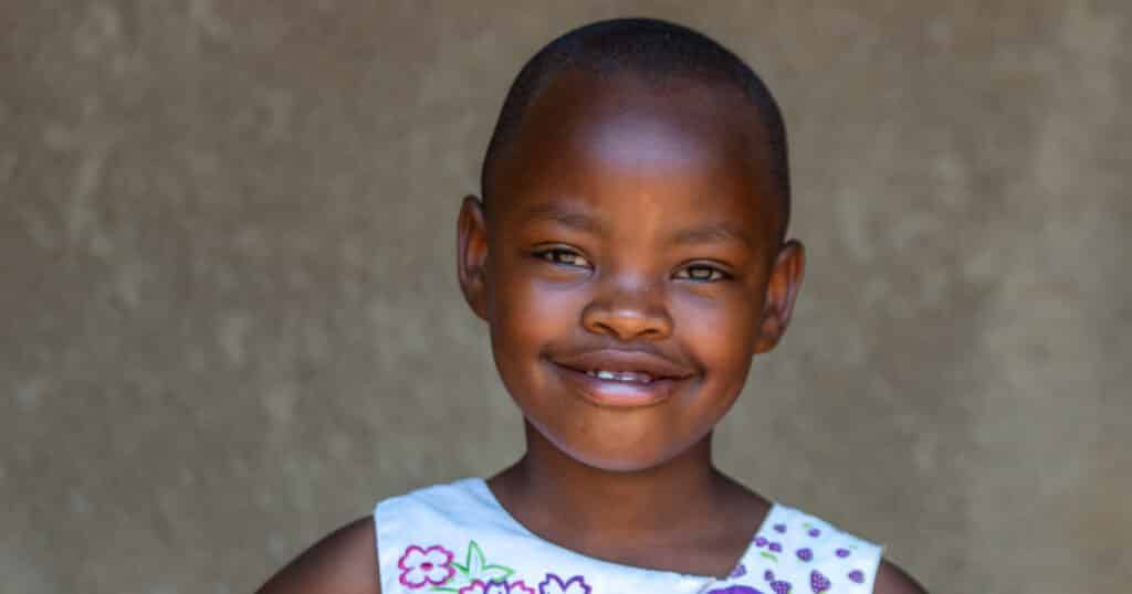 Uwase, a young girl from Rwanda, smiles warmly at the camera.