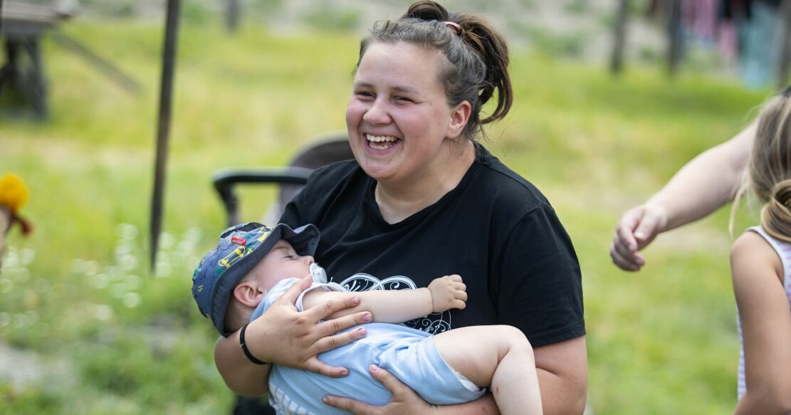 Tina* laughing joyfully with baby Serhii* in her arms, Ukraine.