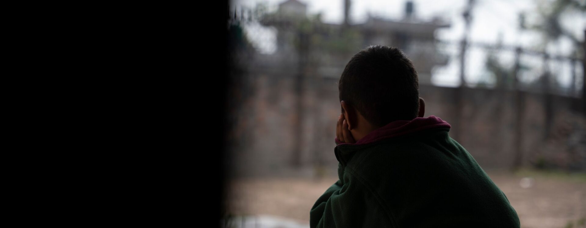 Image of a young person in silhouette staring out